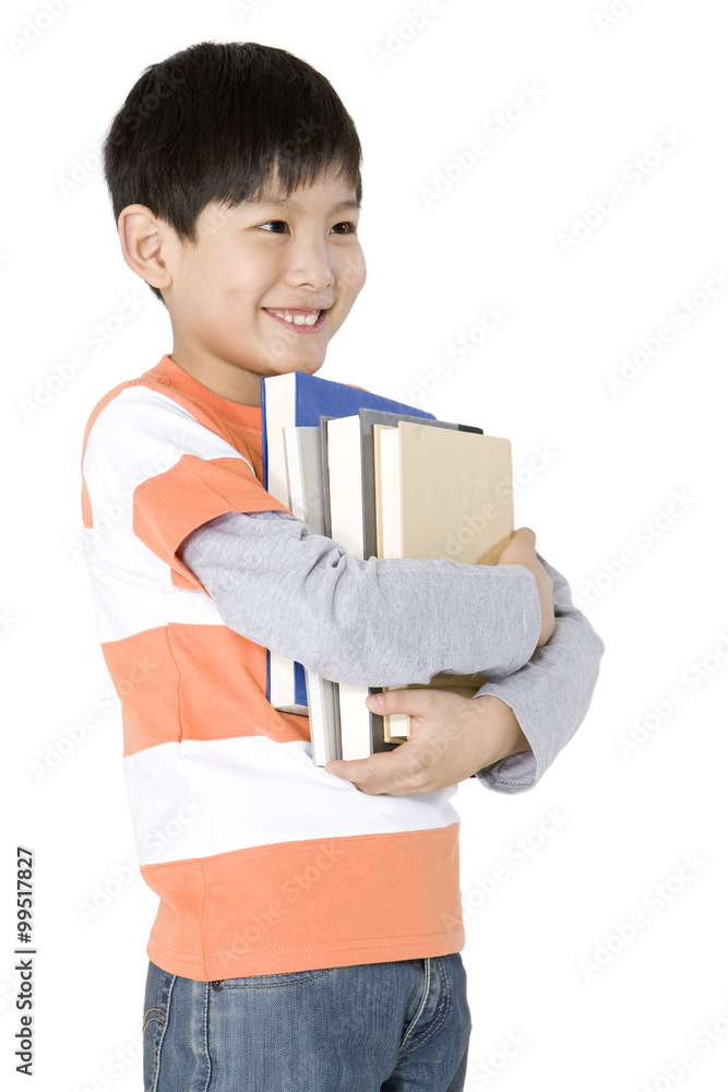 Happy young boy carrying a stack of books