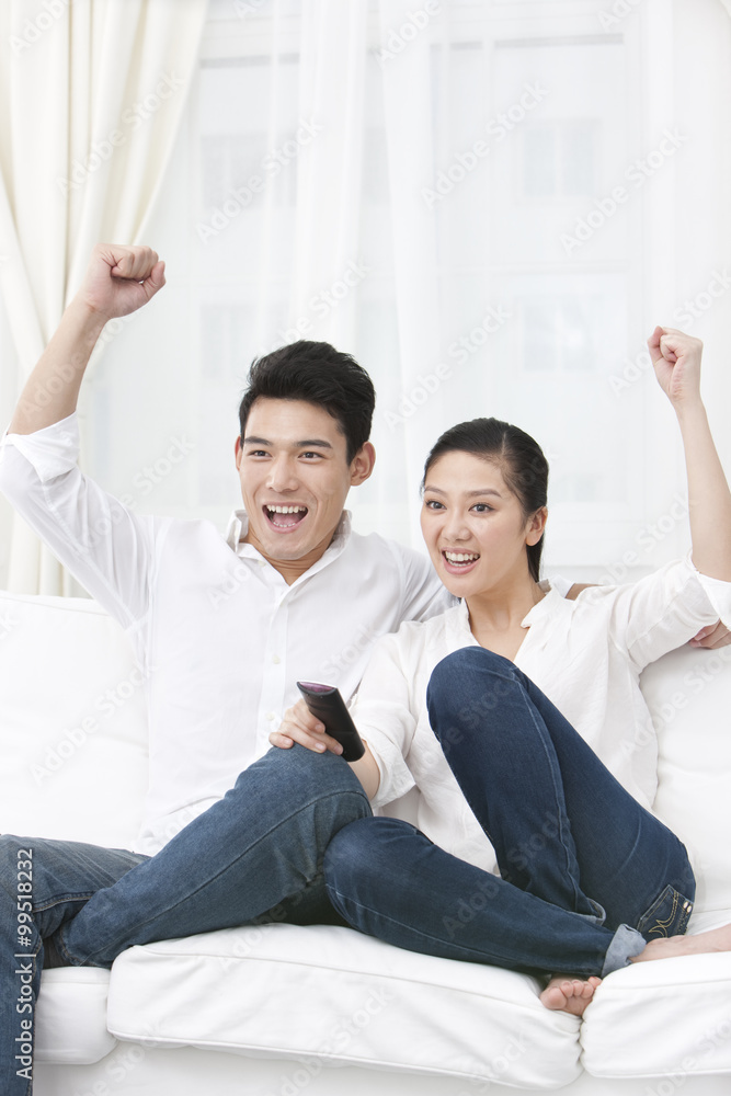 Happy young couple watching TV together