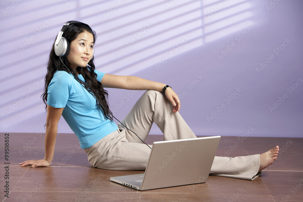 Woman Sitting On Floor With Computer Wearing Headphones