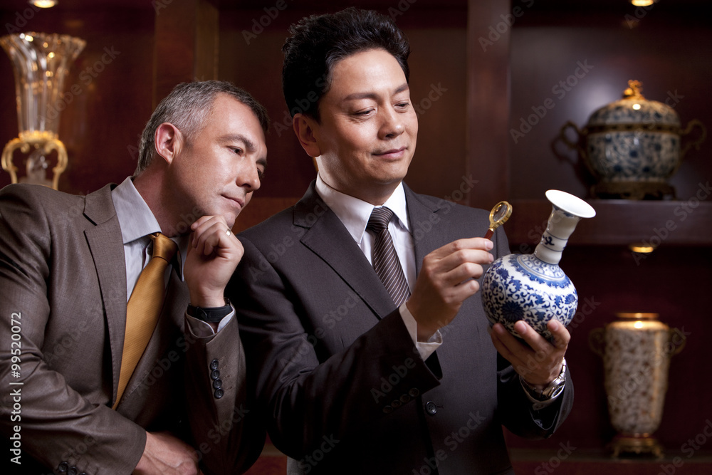 成熟的商人欣赏一个古董中国花瓶