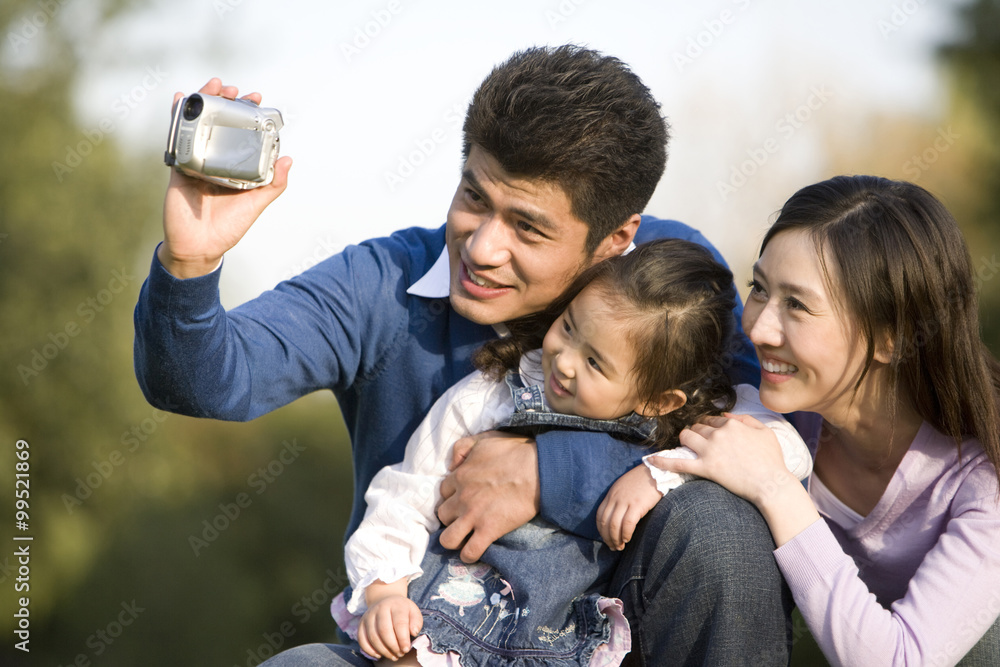 年轻家庭在公园制作家庭视频