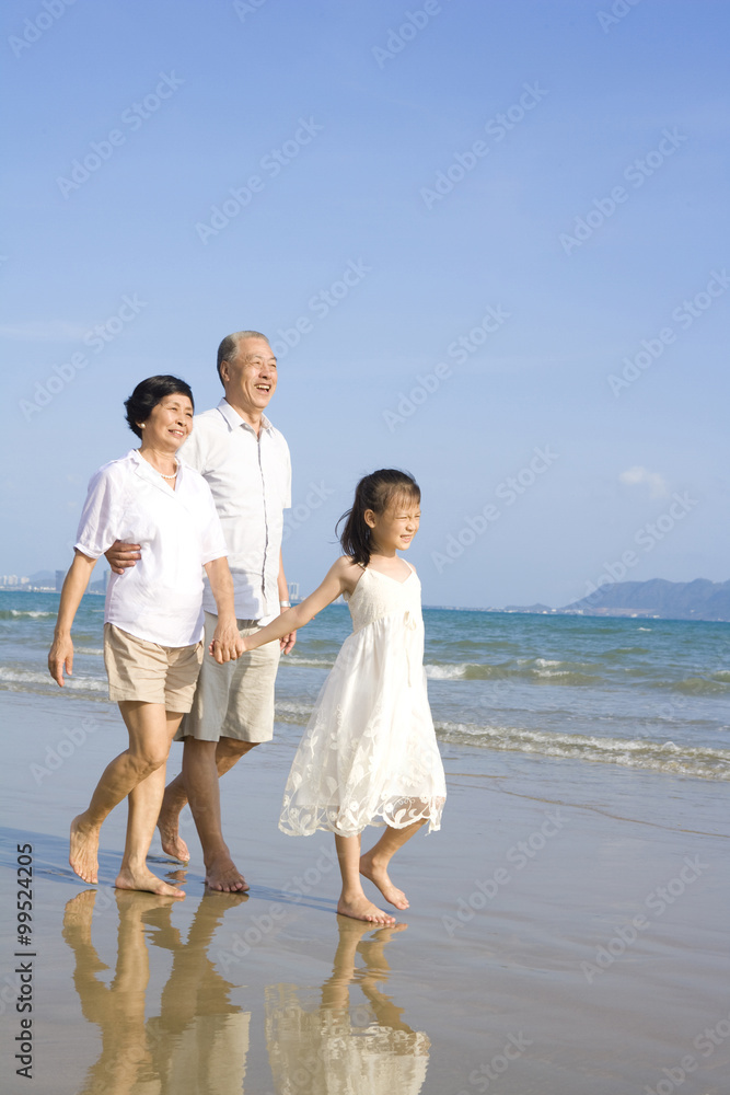 爷爷奶奶和孙女在海滩上散步