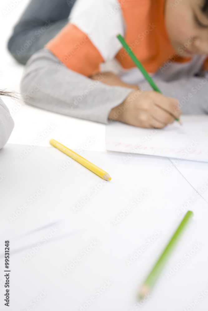 彩色铅笔在前景中，男孩在背景中着色