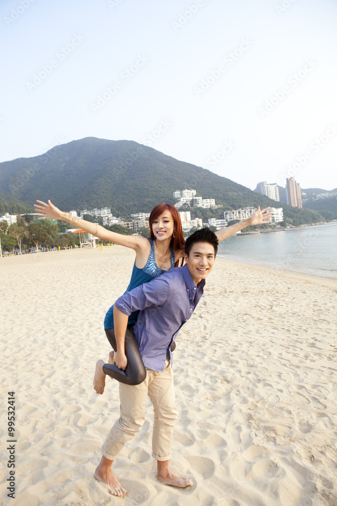 Sweet young couple playing piggyback on the beach of Repulse Bay, Hong Kong