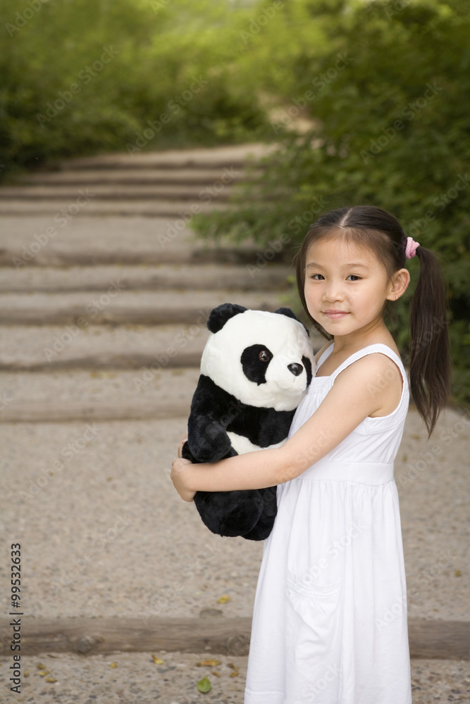 站在公园里抱着熊猫软玩具的年轻女孩