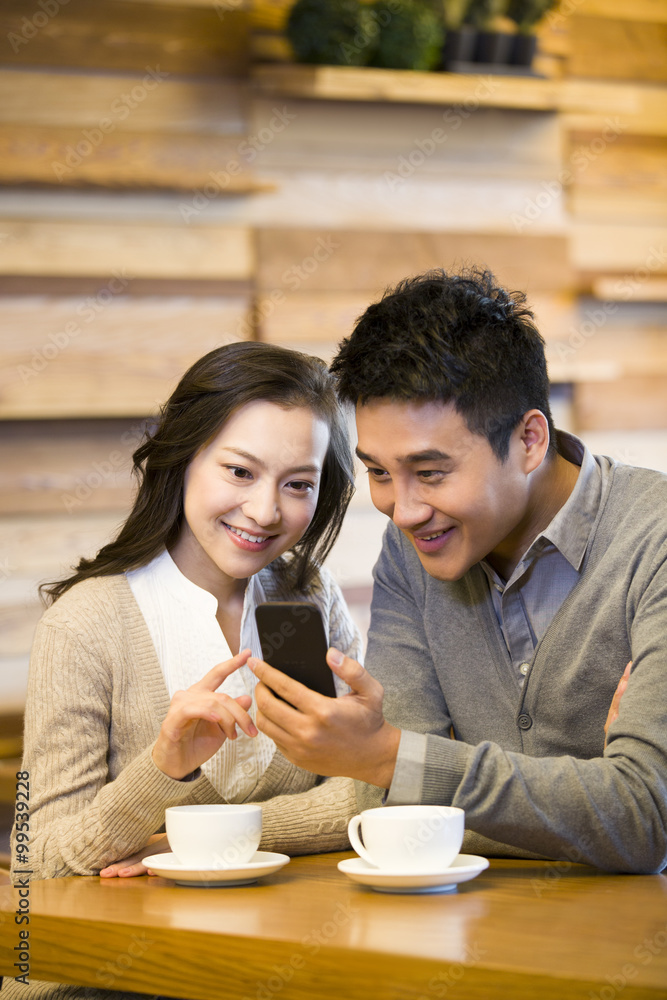 幸福的年轻情侣在咖啡馆用智能手机
