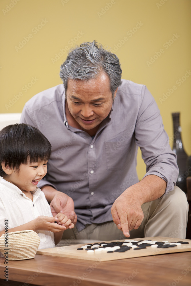 小男孩和爷爷一起玩中国围棋