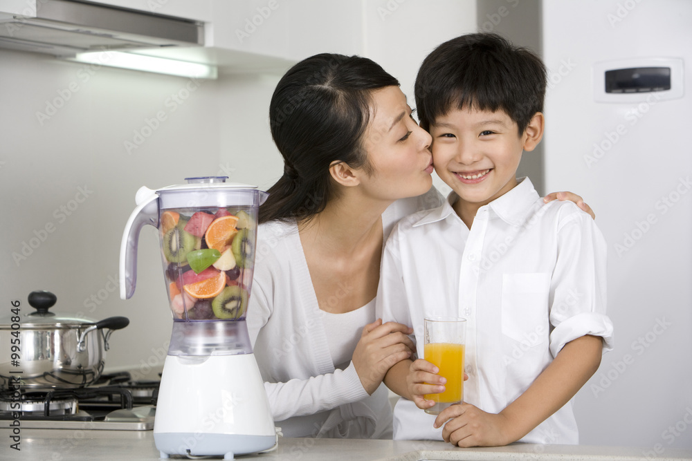 Mother and son making fresh fruit juice in kitchen