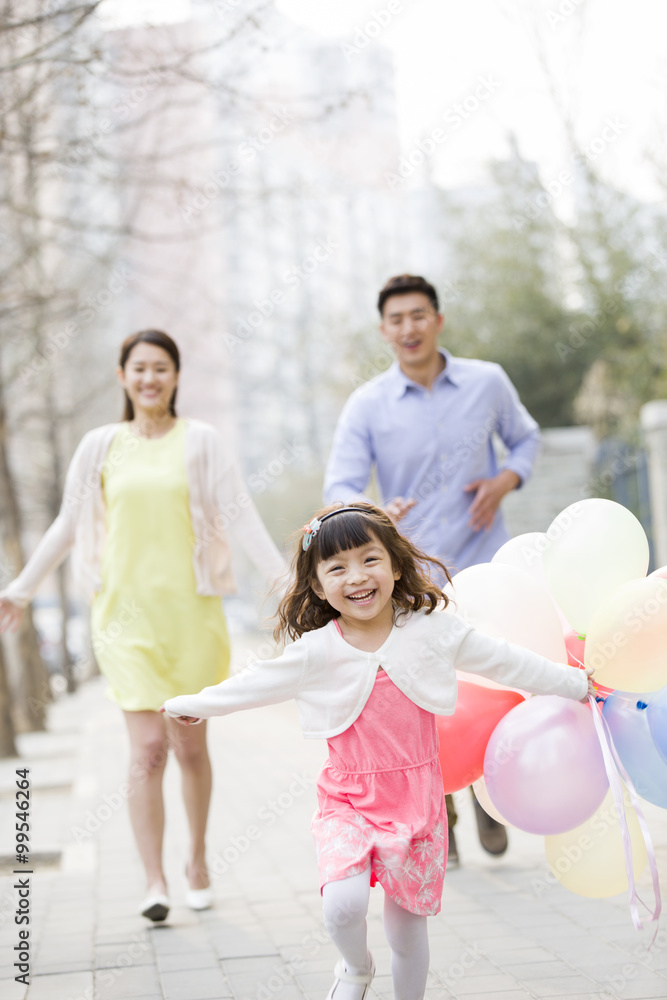 快乐的年轻家庭用气球奔跑