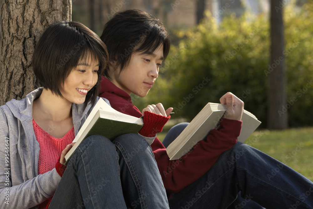 年轻情侣在公园看书