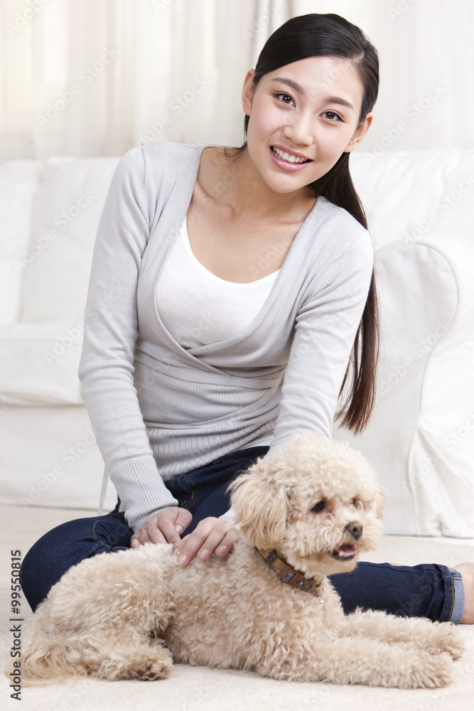 Young woman playing with a pet toy poodle