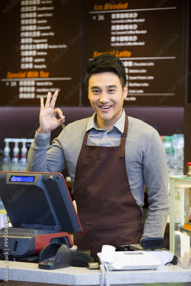 Male coffee store clerk doing OK sign