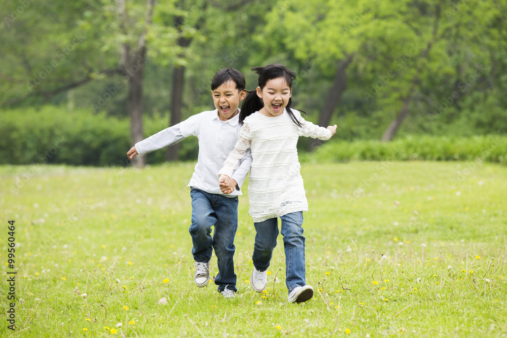 快乐的孩子们牵着手在草地上奔跑