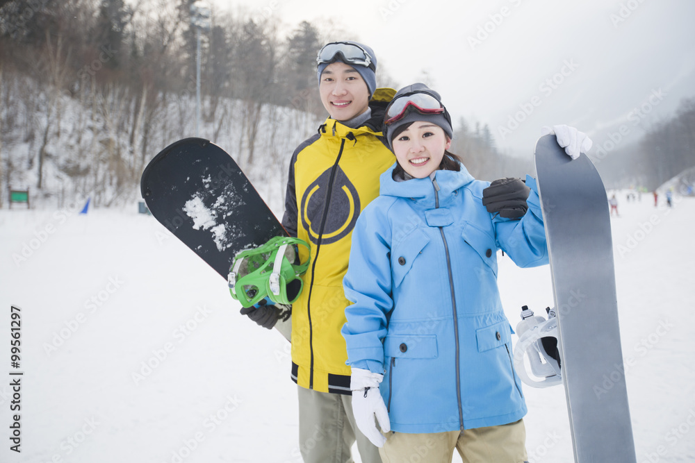 雪地上带滑雪板的年轻情侣