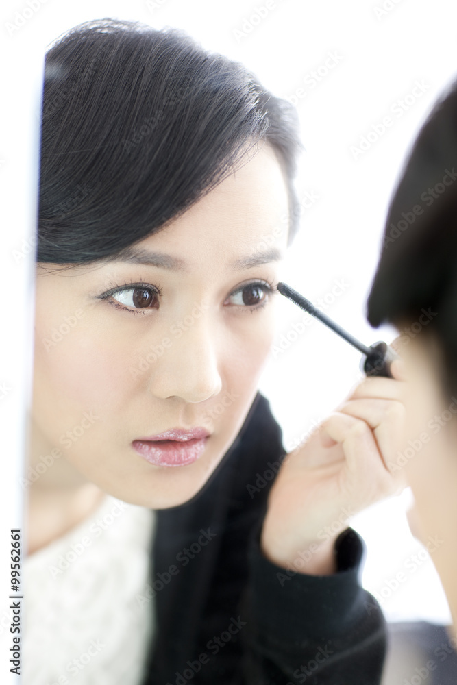 年轻女性在镜子前涂睫毛膏