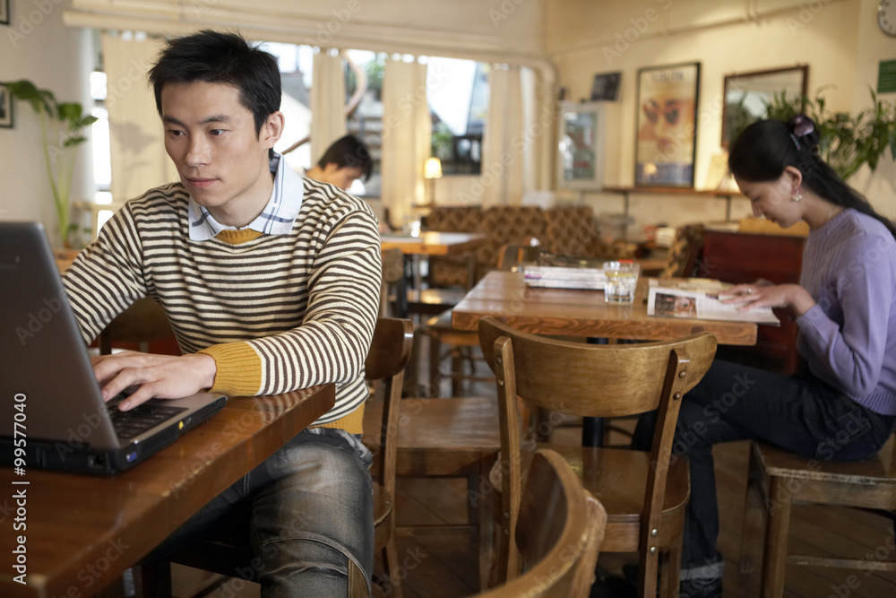 年轻人坐在咖啡馆的笔记本电脑上