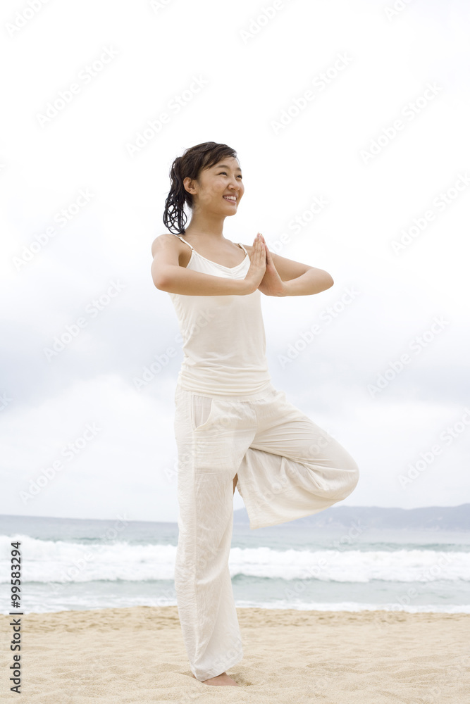 A woman practicing yoga at the beach