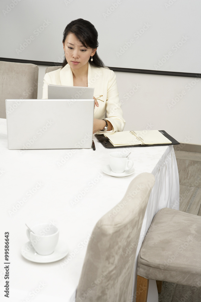 女商人在餐桌上使用笔记本电脑