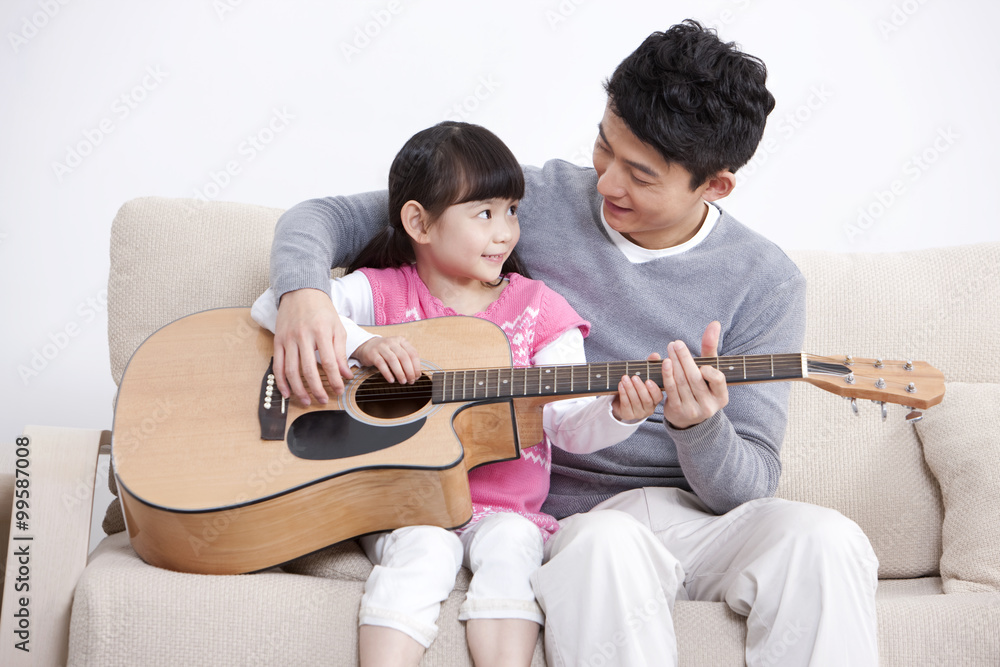快乐的父亲和小女儿在客厅弹吉他