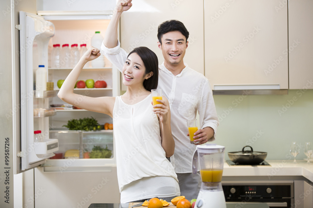 Young couple cheering with orange juice