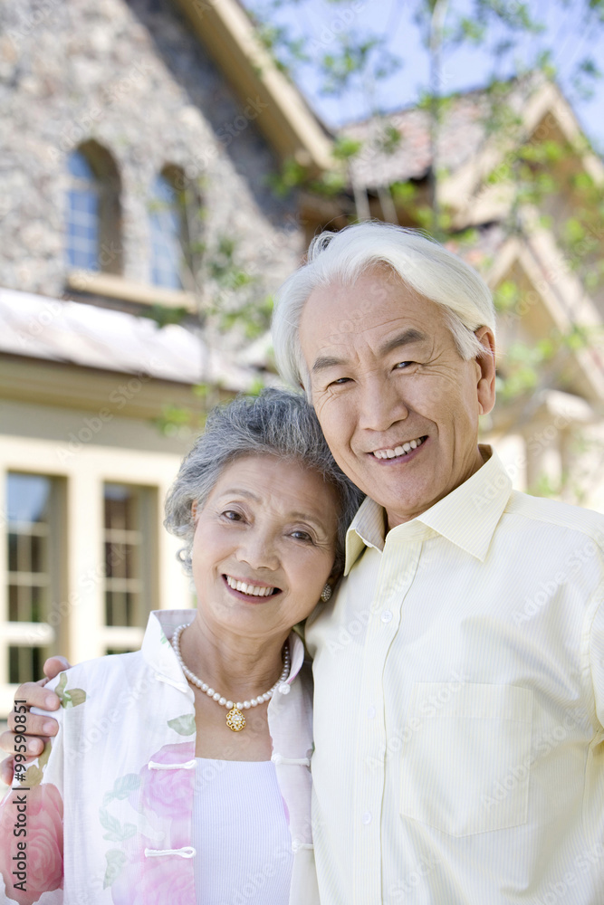 Portrait of senior couple in front of house