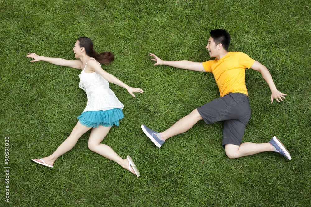 年轻情侣在草地上玩追逐游戏