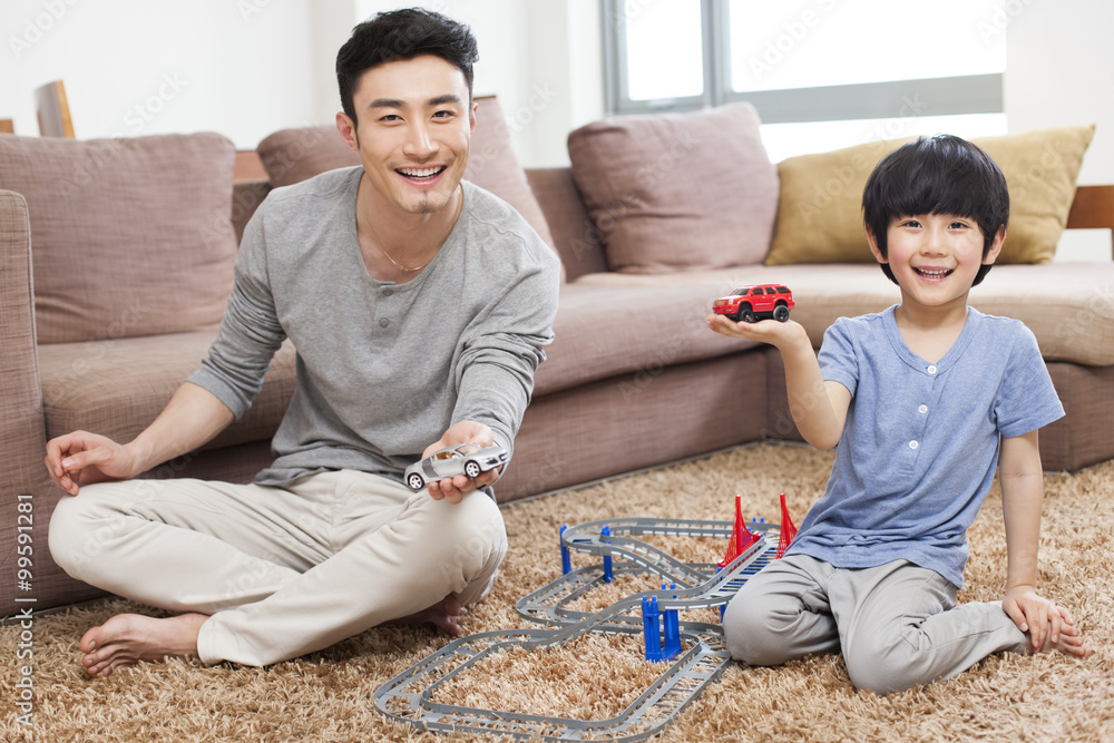 Father and son playing toy car in living room