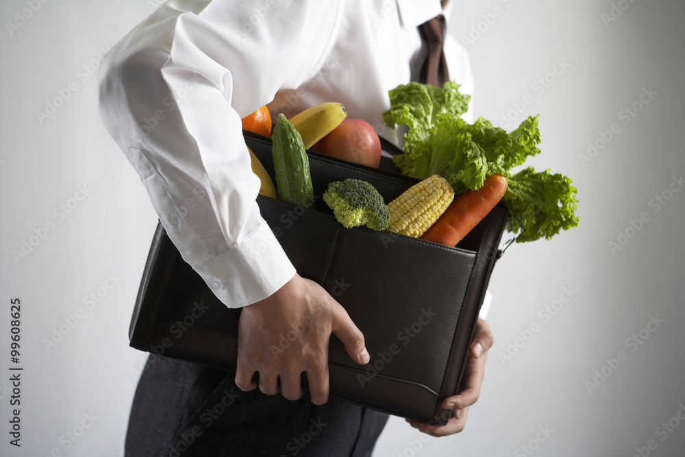 一个商人拿着装满蔬菜的公文包的特写