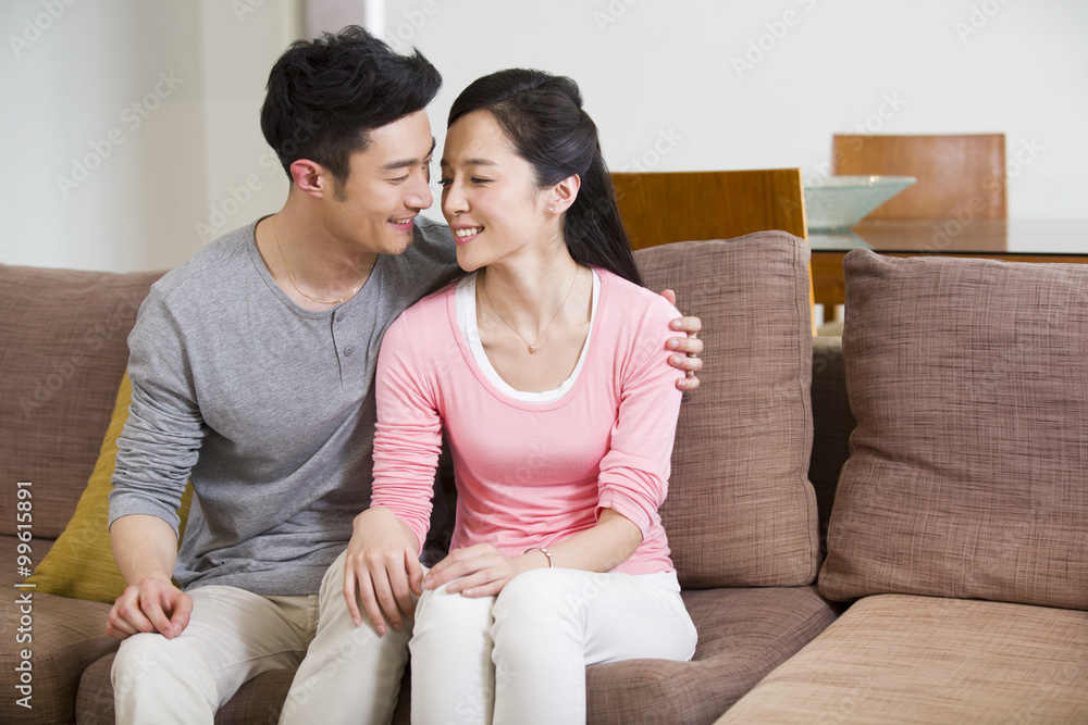 幸福的年轻情侣坐在沙发上