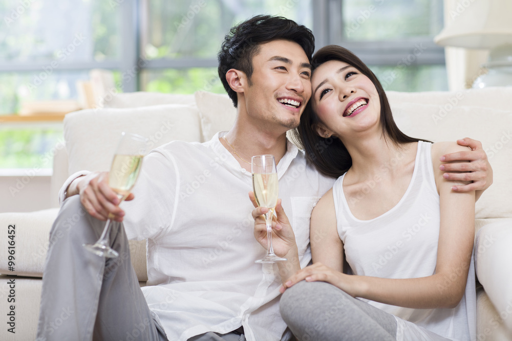 快乐的年轻夫妇在客厅喝香槟