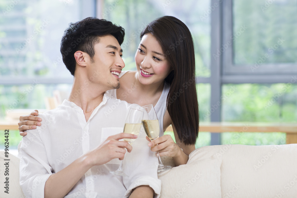 幸福的年轻夫妇在客厅喝香槟