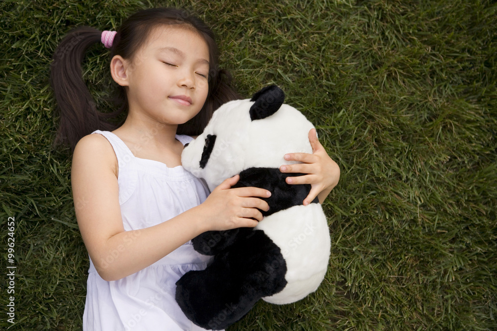 Young Girl Standing In Park Holding Panda Soft Toy