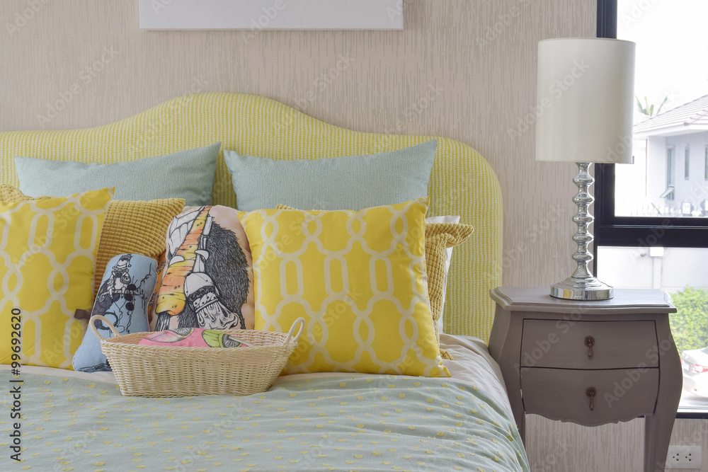 经典风格床上的黄绿色图案枕头和床头柜上的阅读灯