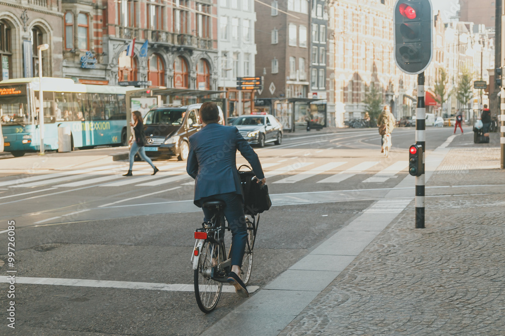 一个穿着西装骑自行车的男人在城市里站着，直到红灯亮起。他去上班了