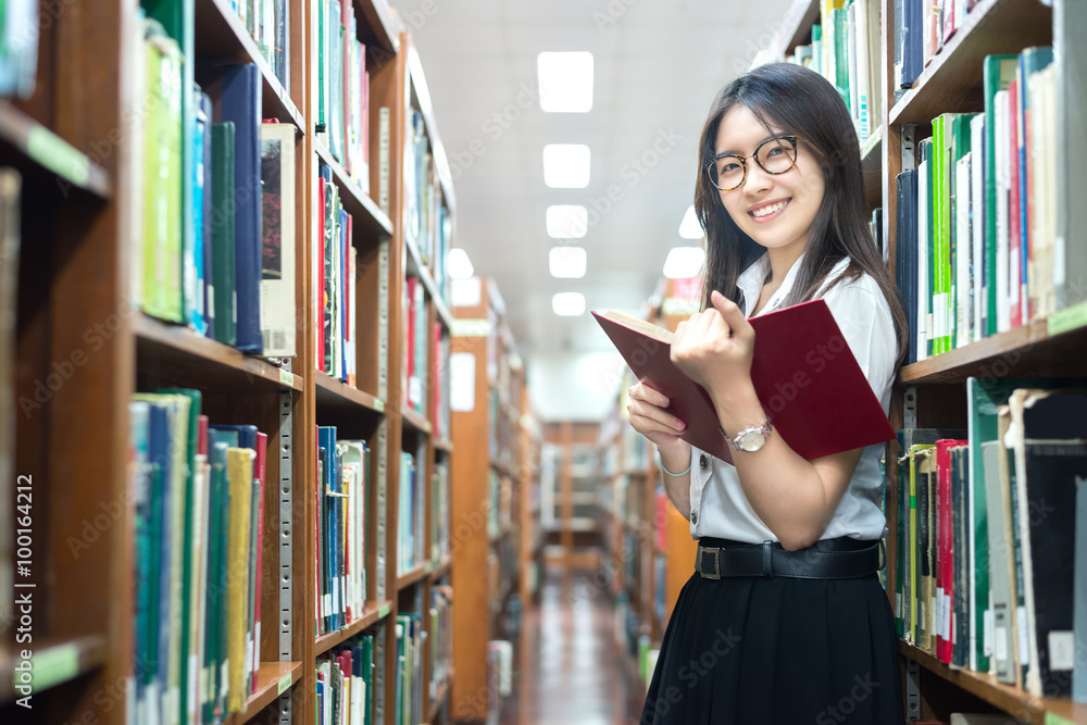 穿着制服的亚洲学生在大学图书馆阅读
