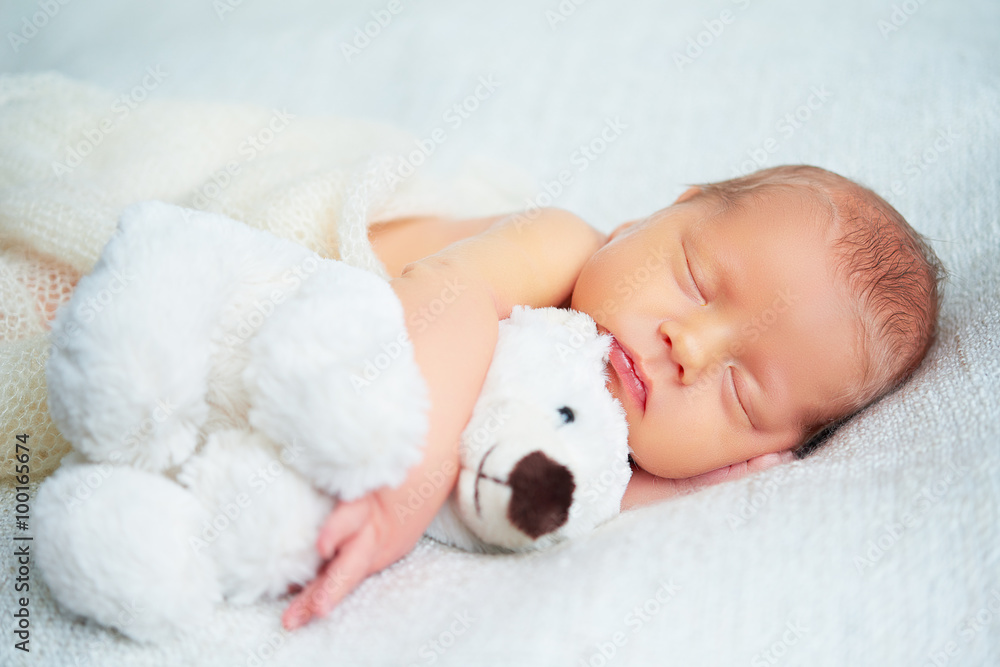 可爱的新生儿和玩具泰迪熊睡觉
