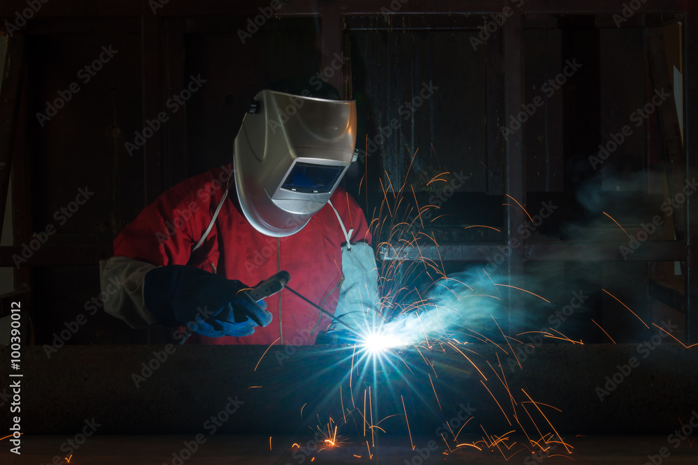 戴防护面罩的工人在工厂焊接金属