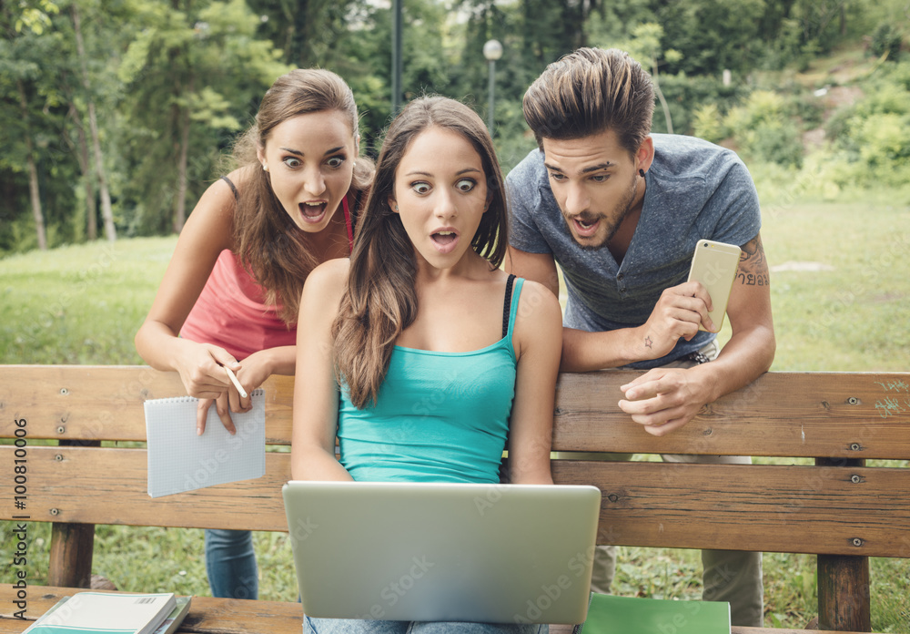 Shocked teenagers using a laptop