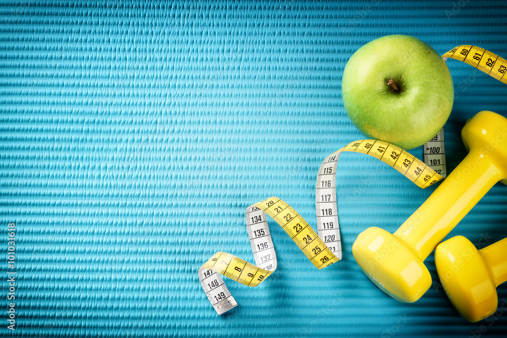 Fitness background with dumbbells, measuring tape and apple. Hea