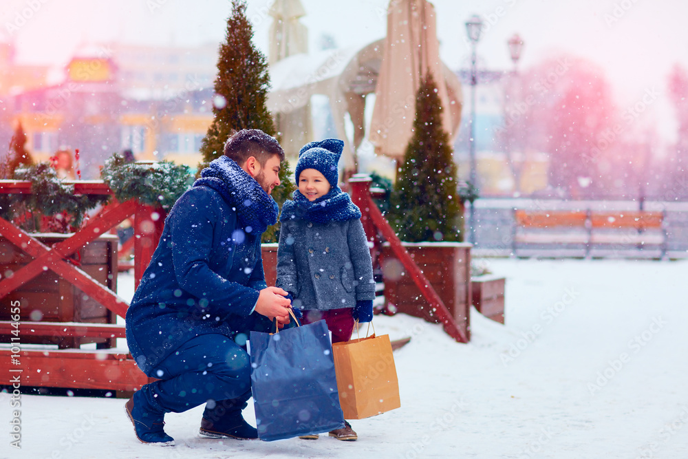 父亲和儿子在城市的冬季购物，节日季节，买礼物