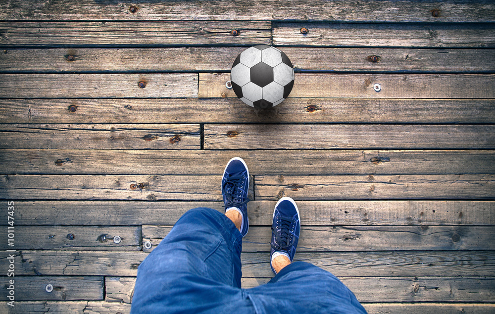 一个男人在旧木瓦地板上踢足球的视角。