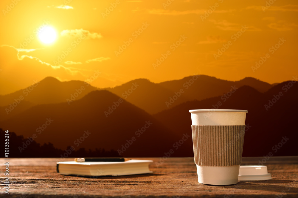 日出时山背景的纸杯咖啡