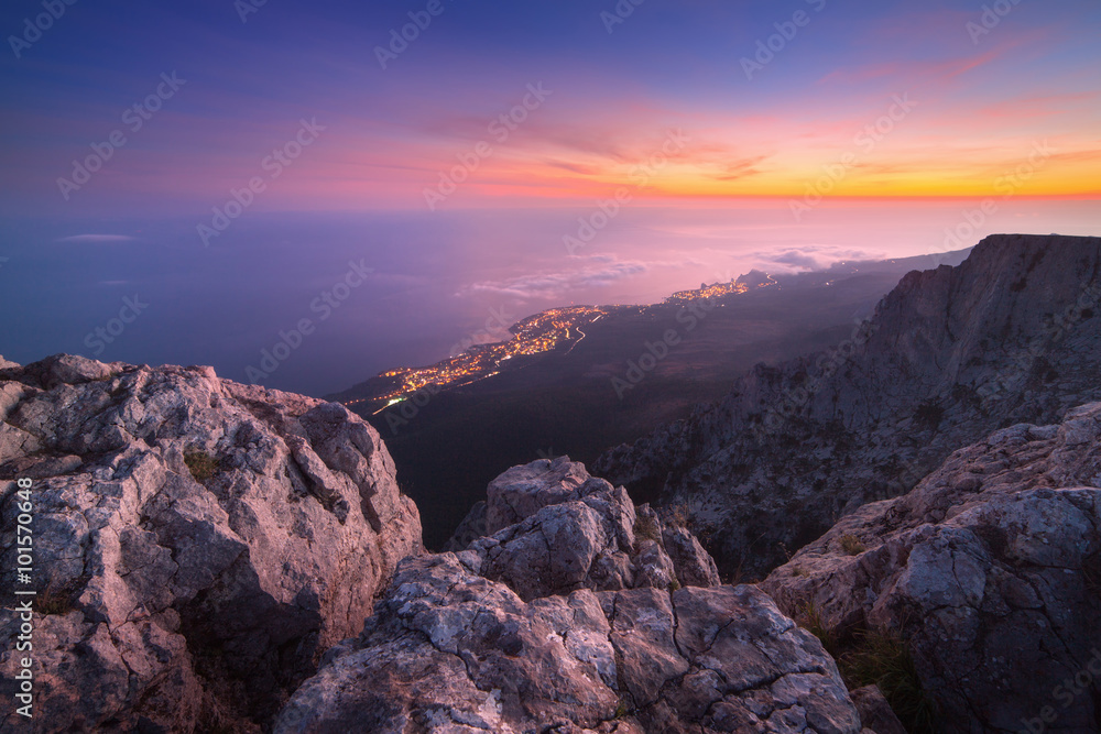Beautiful night landscape on the top of mountains with sea, colorful sunset and low clouds. Nature b