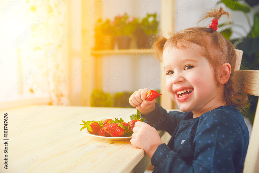快乐的小女孩在夏日家庭厨房吃草莓
