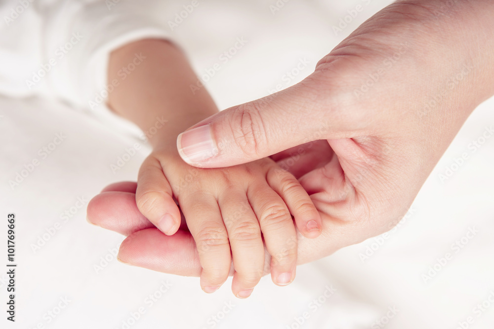 婴儿的手轻轻握住成年人的手指（焦点柔和且模糊）