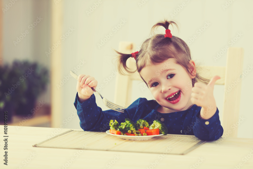 快乐的小女孩喜欢吃蔬菜并竖起大拇指