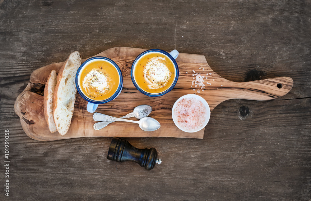 自制南瓜奶油汤，搪瓷马克杯，香草和新鲜面包片放在橄榄板上