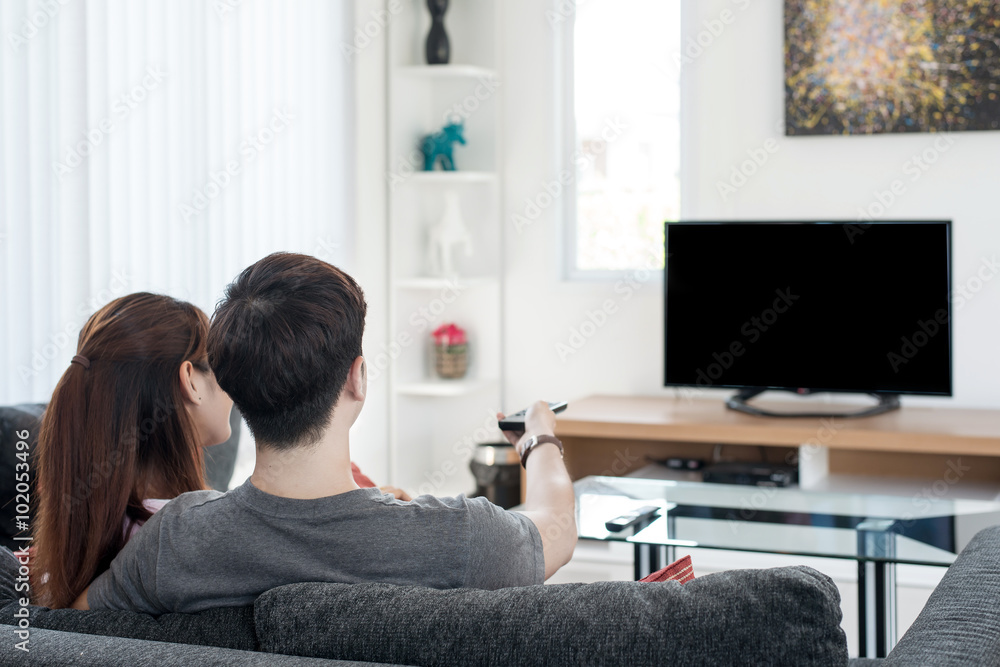 年轻的亚洲夫妇在家里看电视电影