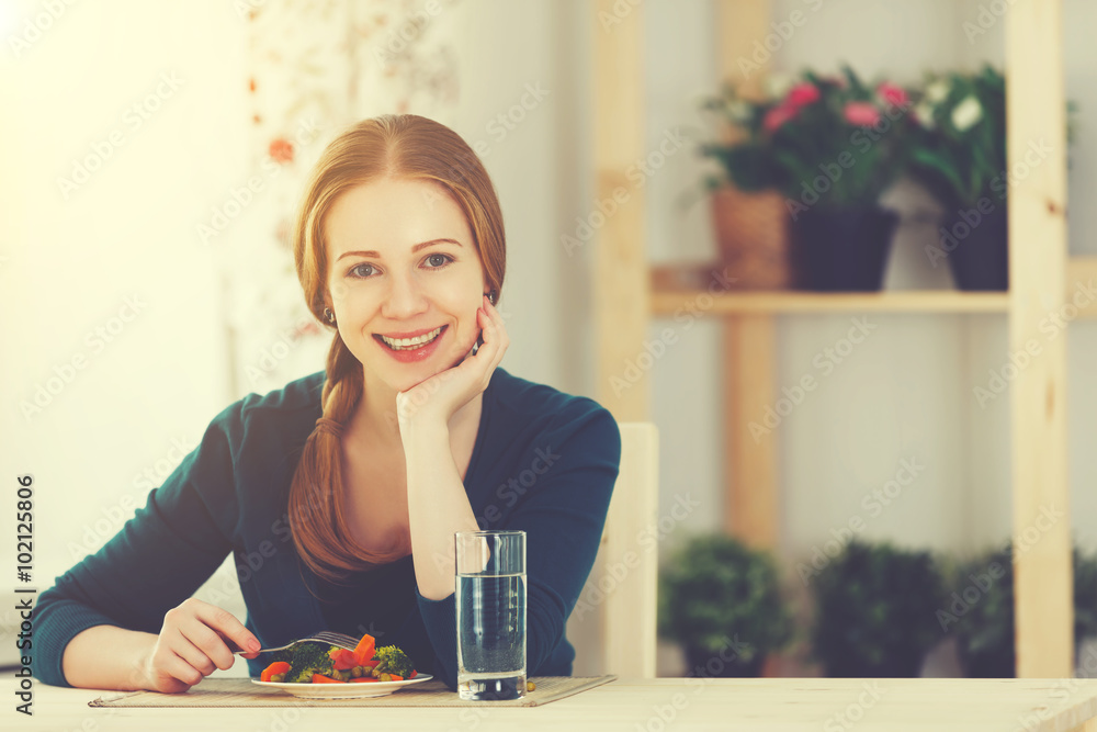 young healthy woman eats vegetables at home in the kitchen