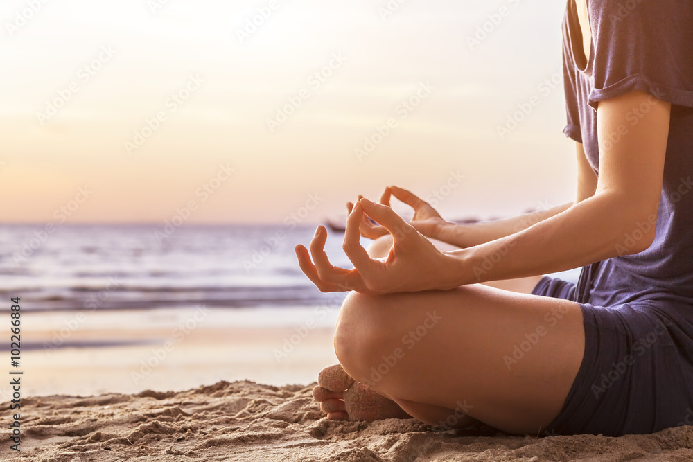 Young woman practicing yoga on the beach for harmony
